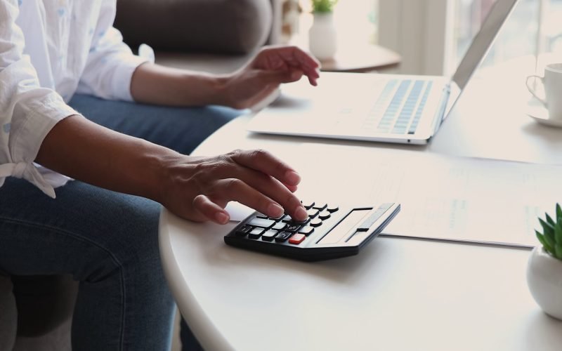 closeup-of-young-woman-hands-type-on-laptop-and-calculator-SBI-351619816
