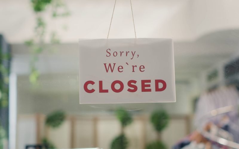 sorry-we-are-closed-sign-in-empty-fancy-fashion-boutique-with-stylish-formal-clothes-m-SBI-351359626